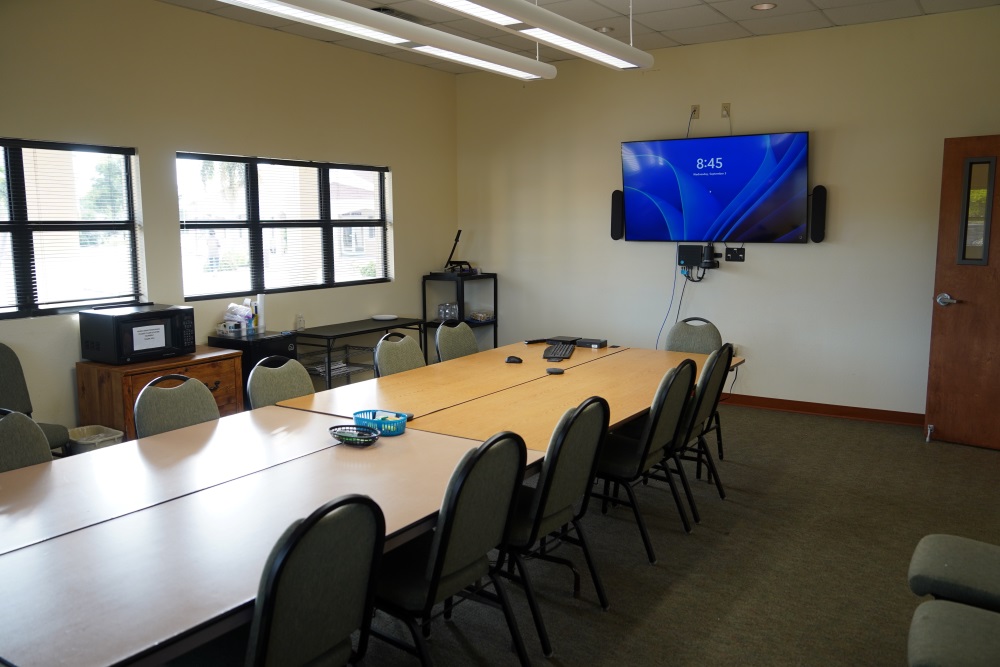 Small meeting room with a large wall-mounted projection screen and a door to the side